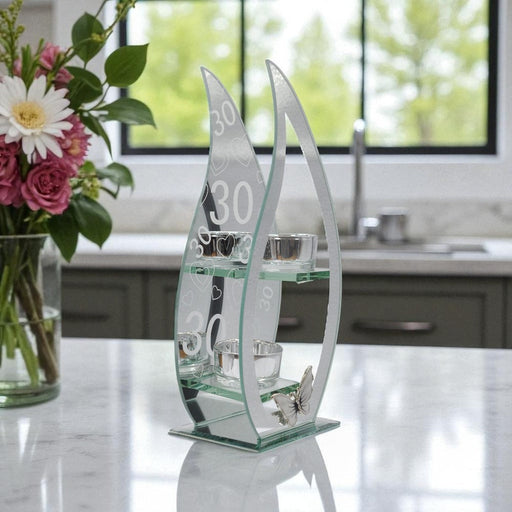 Decorative glass piece with a curved teardrop design and embedded with the numbers 30 on a mirror background