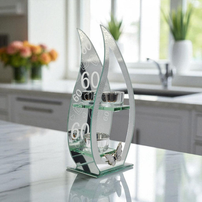 Decorative glass tealight holder with curved teardrop design and the numbers '60' on a mirrored background